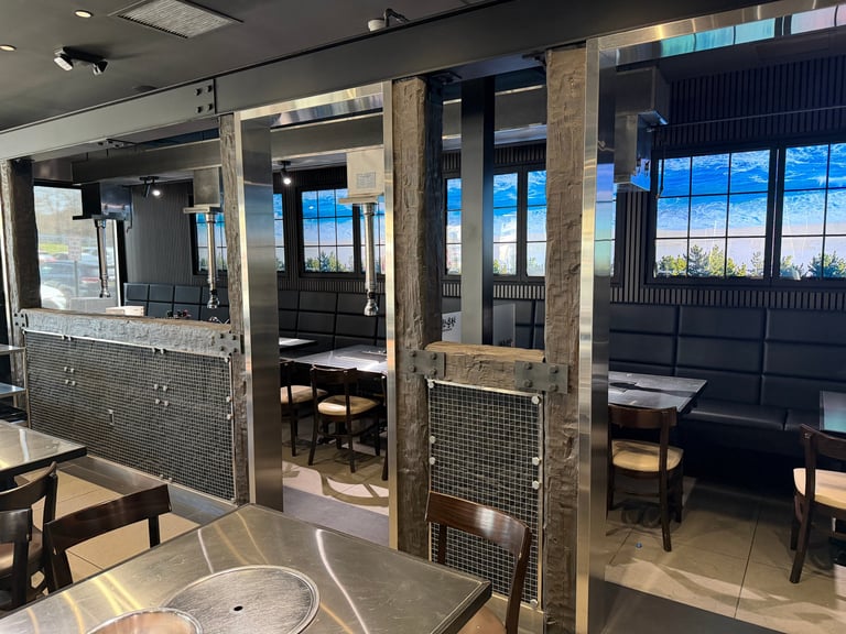 Modern restaurant interior with wooden partitions, dining tables, floor-to-ceiling windows overlooking cityscape